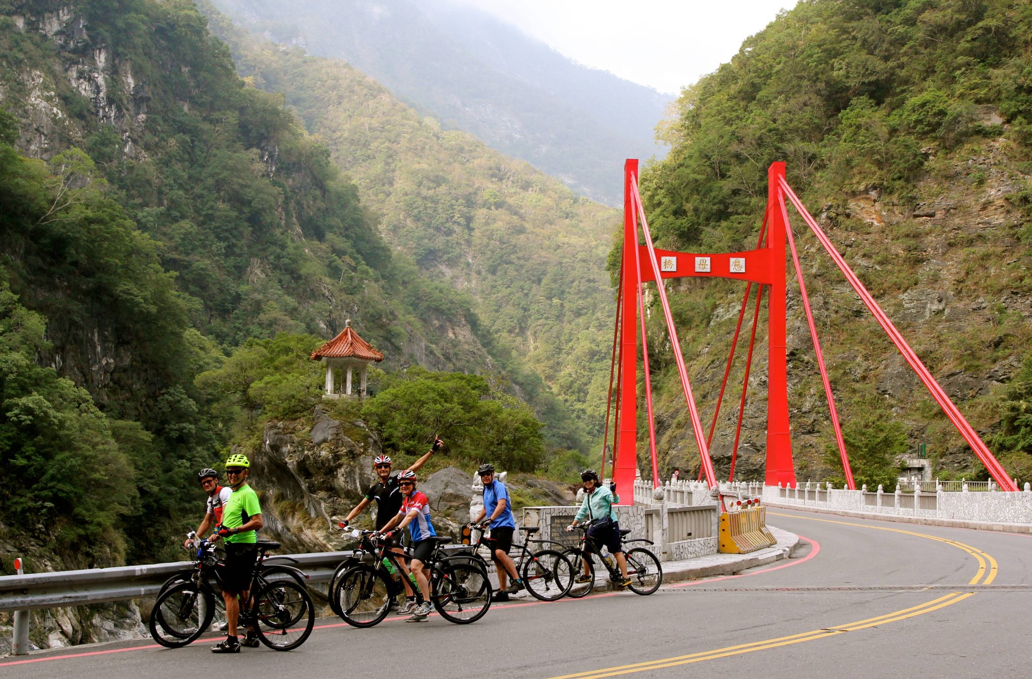 Cyclists stopped after red suspension bridge in Taroko Gorge National Park