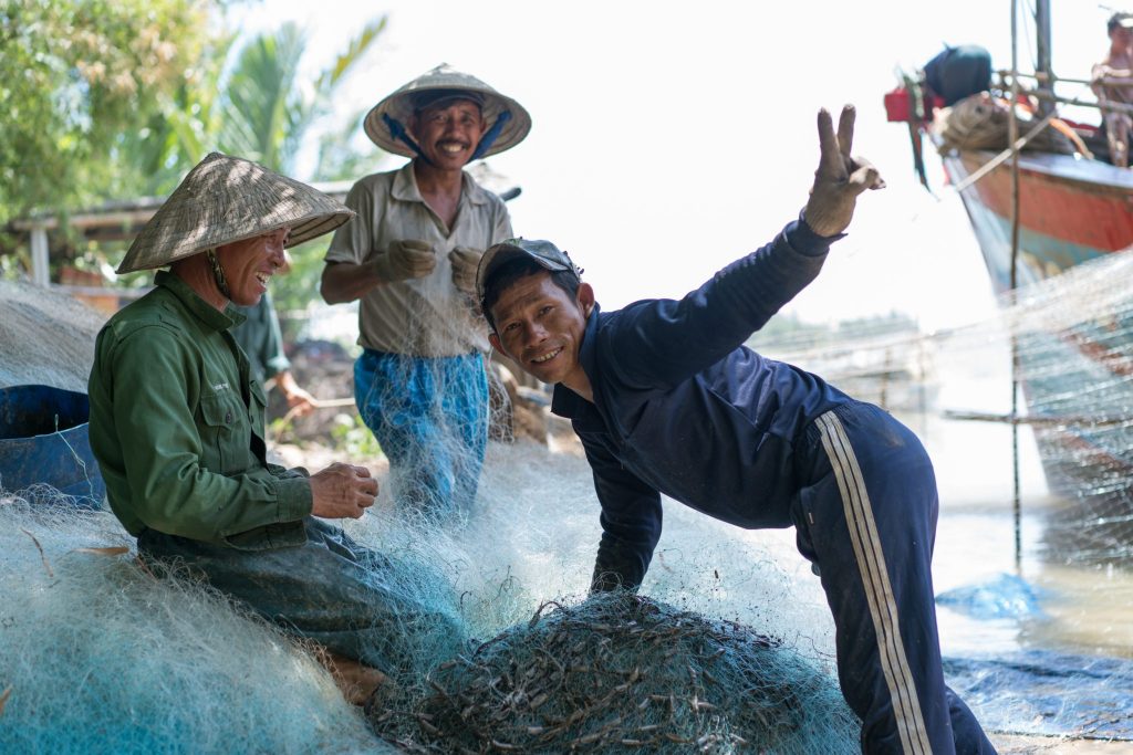Three local men, two in hats, with fishing net