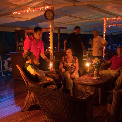 People eating and drinking by candlelight on deck of riverboat