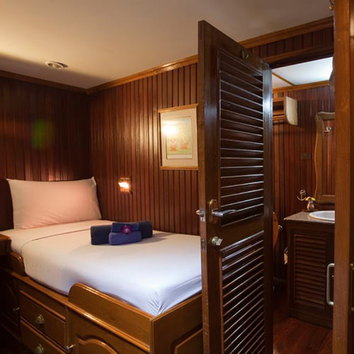 Cabin on ship, with bed and wooden walls and bathroom