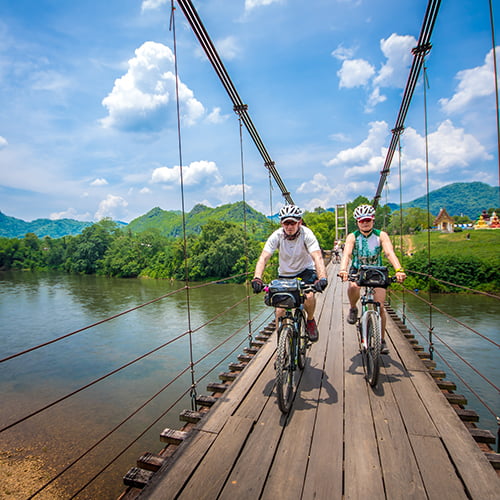 Two cyclists on the Bridge Over the River Kwai in Thailand