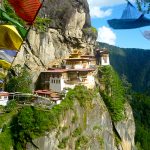 Tiger Nest monastery built into cliffside with prayer flags in forefront