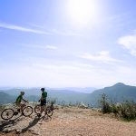 Two cyclists parked on hill overlooking mountains of Sri Lanka