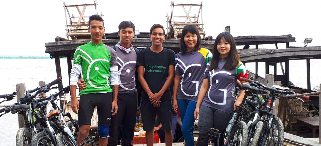 Five people on barge in Myanmar Grasshopper Adventures cycling jerseys