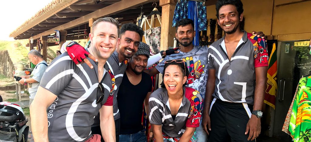 Group of cyclists and guides in Sri Lanka in front of souvenirs