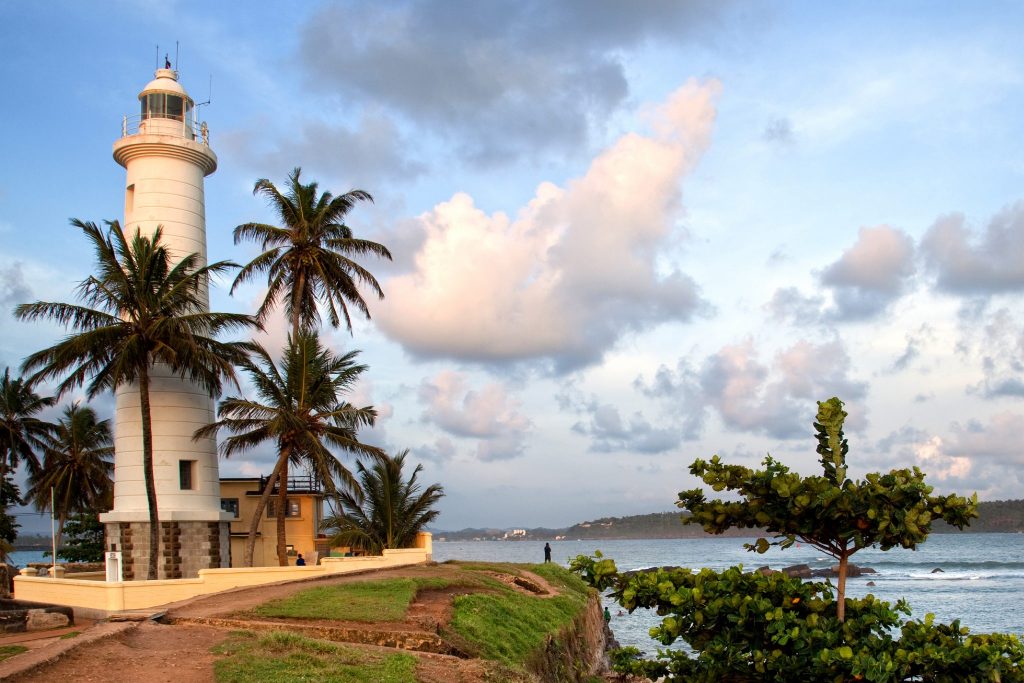 Lighthouse with palm trees near water in Galle
