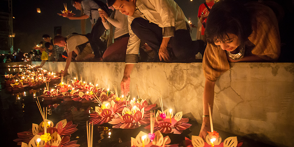Releasing lanterns into the Chao Phaya river in Bangkok Thailand during Loy Kratong festival 