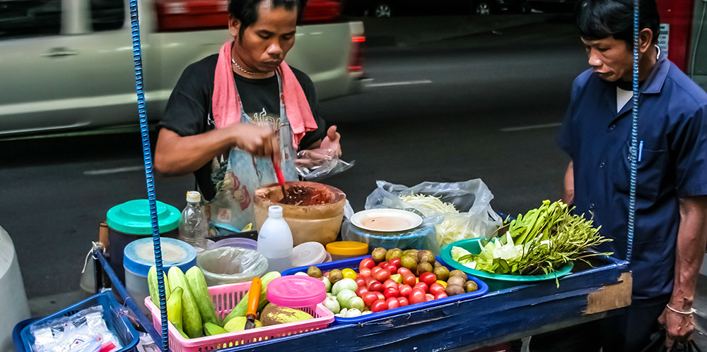 a food vendor in Bangkok preparing a Thai Green Mango Salad