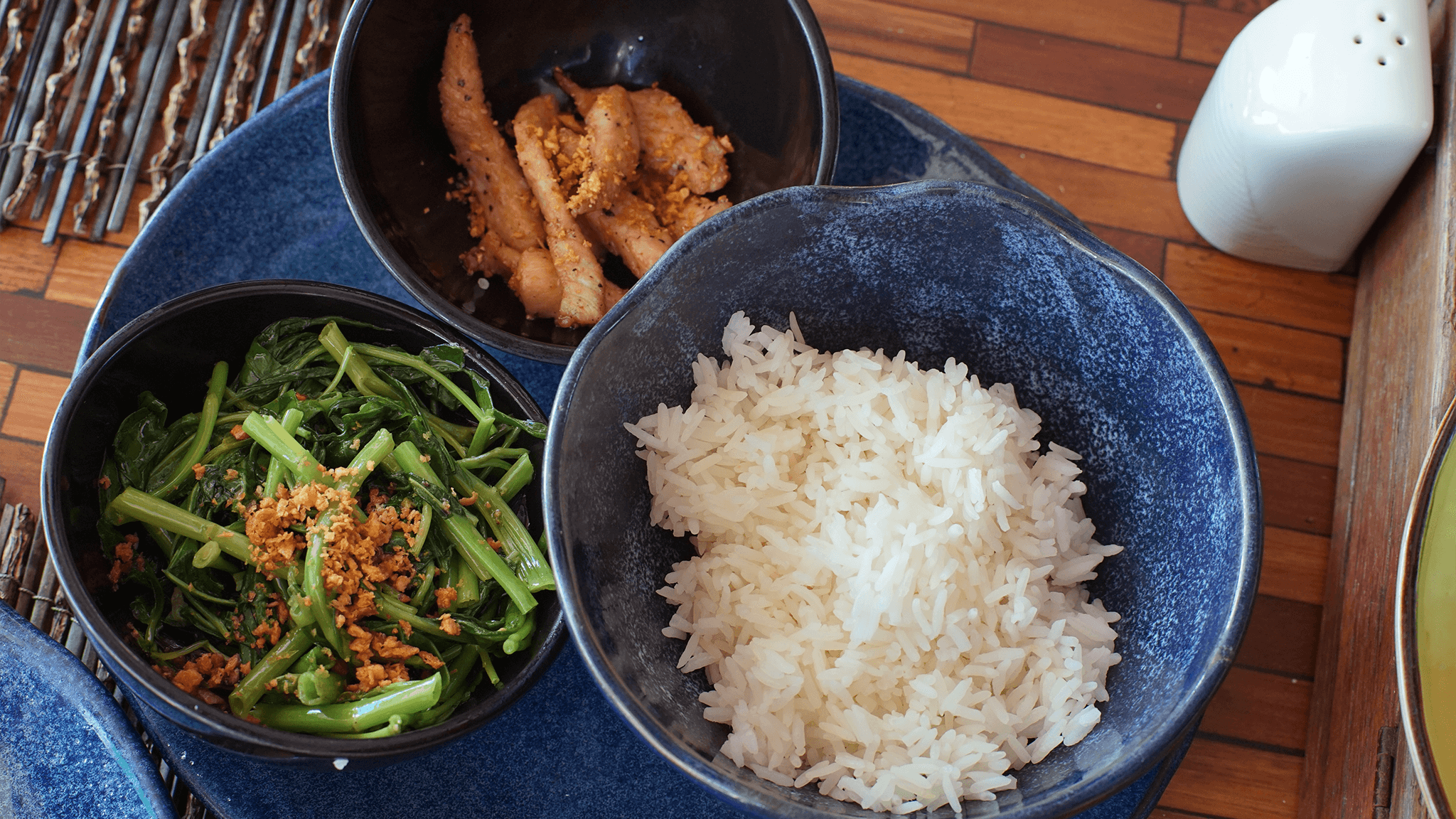Thai breakfast of jasmine rice, morning glory and fried pork