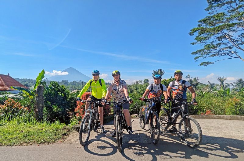 Cyclists pausing to appreciate the striking view of Mount Agung from the backroads in Ubud, Bali