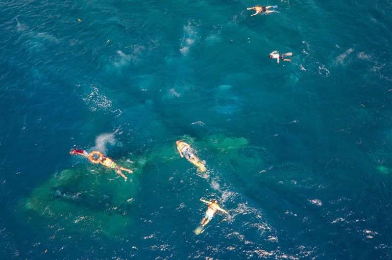 Snorkelers exploring the famous WWII USS Liberty shipwreck in the clear waters of Tulamben, Bali.